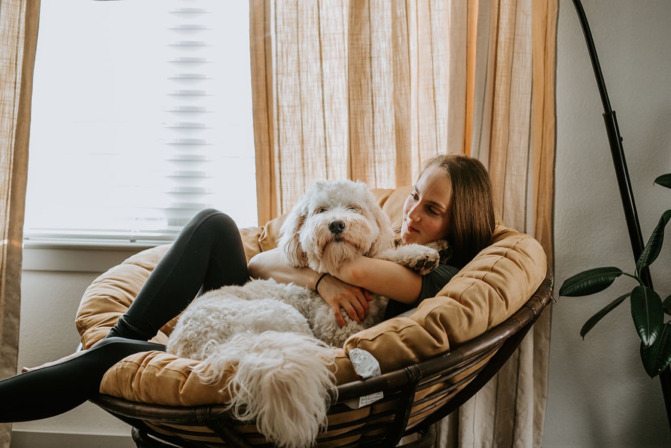 woman holding white fluffy dog on a chair after illness appointment at honnas veterinary